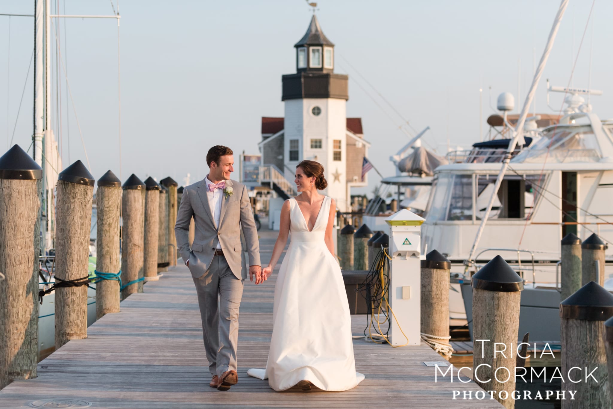 Bride and Groom holding hands with lighthouse in background