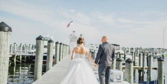 Bride and groom walk on the docks.
