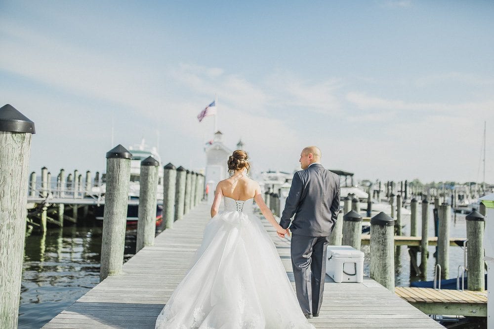 Bride and groom walk on the docks.