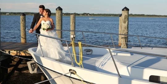 Bride and groom standing on bow of boat.