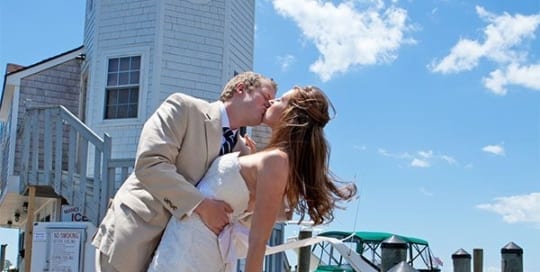 Bride and groom kissing near lighthouse.